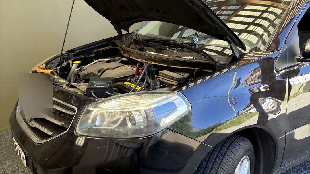 Auto con el capó abierto en una cochera, preparado para el cambio de batería